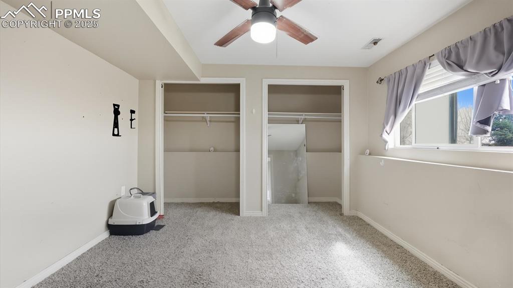 Image 26 of 34: Lower Level Primary Bedroom with neutral carpet, lighted ceiling fan, and d