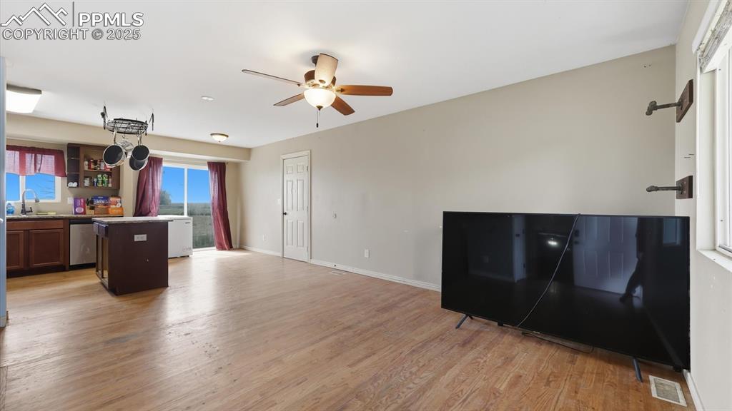 Image 8 of 34: Bright Living Room with wood floor and lighted ceiling fan.