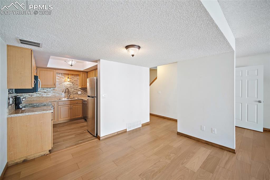 Image 10 of 41: Kitchen with light countertops, light wood-style floors, tasteful backsplas