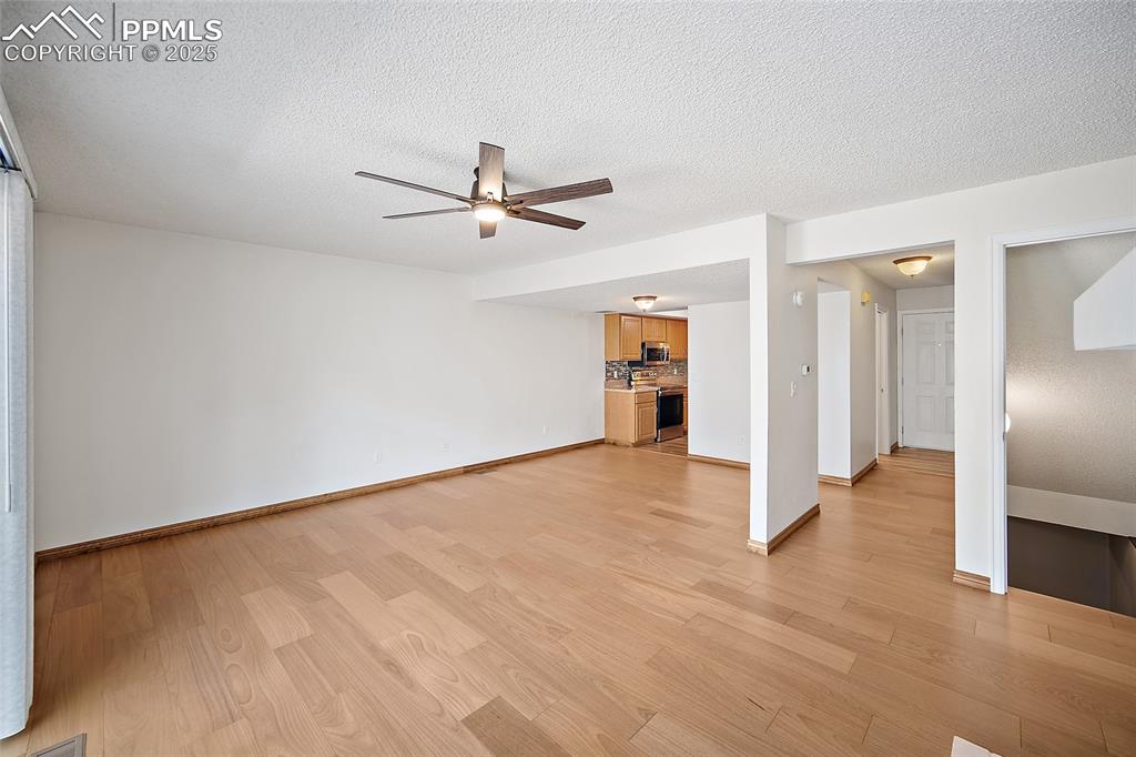 Image 11 of 41: Unfurnished living room featuring a textured ceiling, light wood-style floo