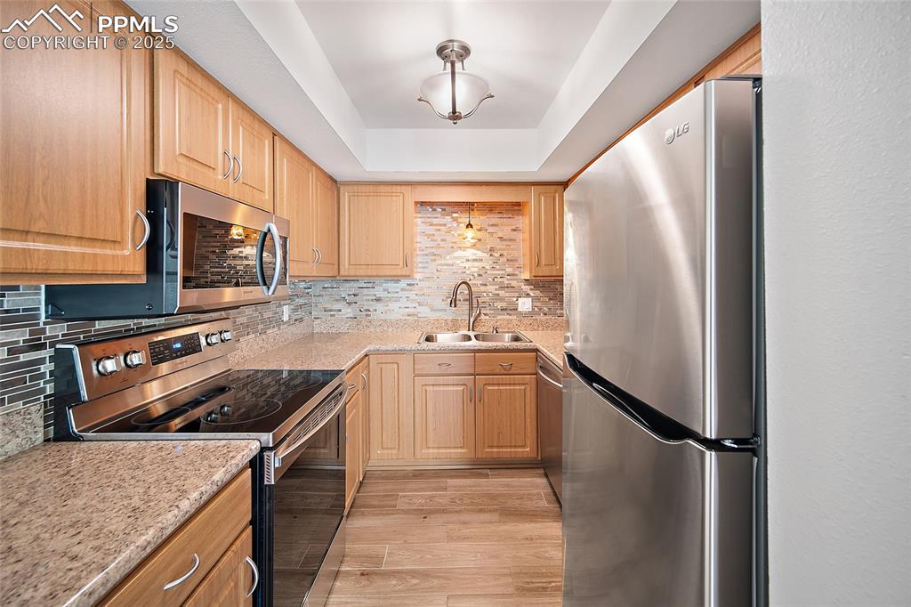 Image 13 of 41: Kitchen featuring appliances with stainless steel finishes, light wood fini