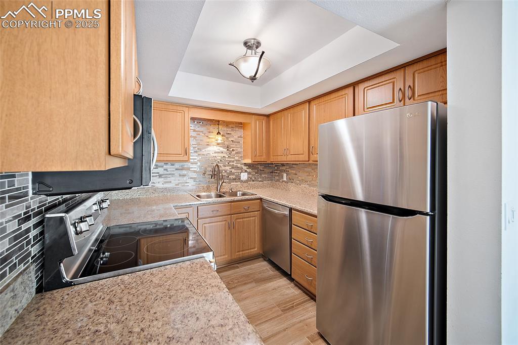 Image 14 of 41: Kitchen featuring stainless steel appliances, a tray ceiling, tasteful back