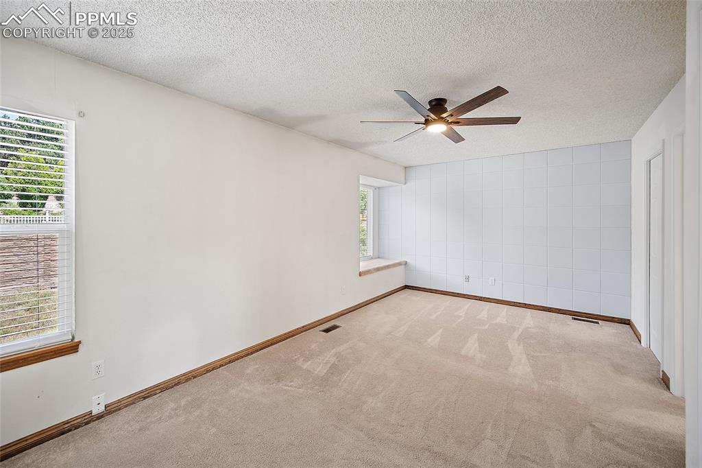 Image 16 of 41: Carpeted empty room with a textured ceiling and ceiling fan