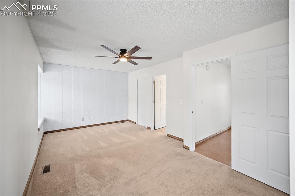 Image 17 of 41: Carpeted empty room featuring a textured ceiling and ceiling fan