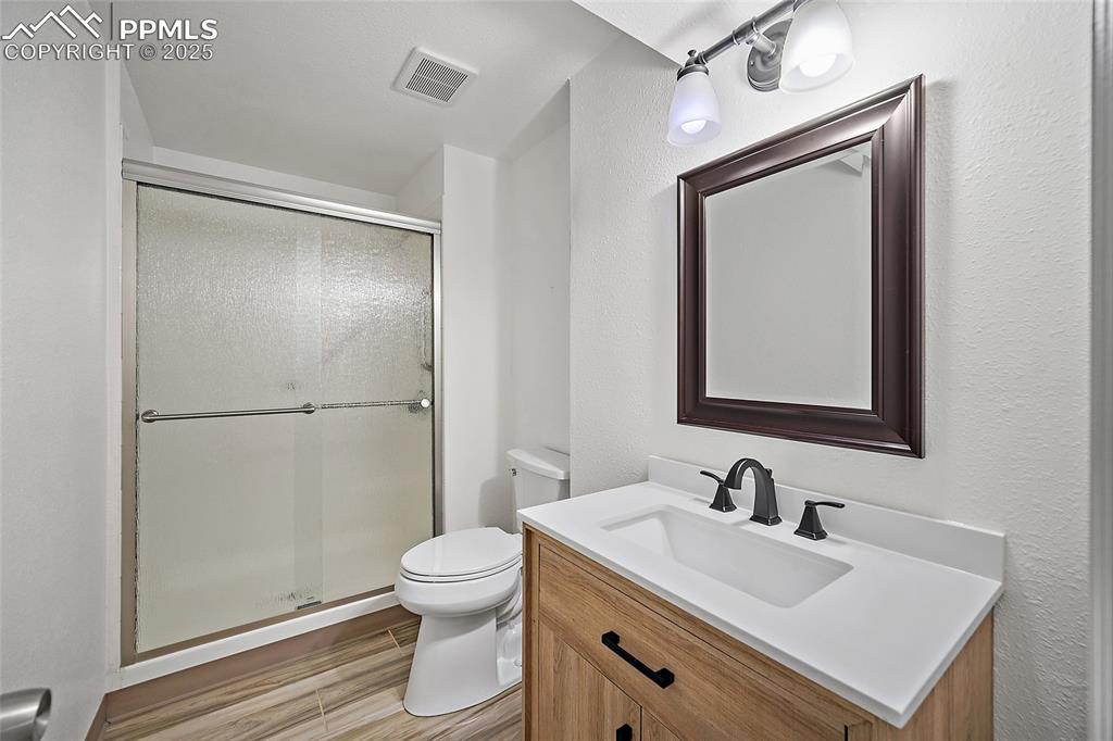 Image 18 of 41: Bathroom featuring vanity, a shower stall, wood finished floors, and a text