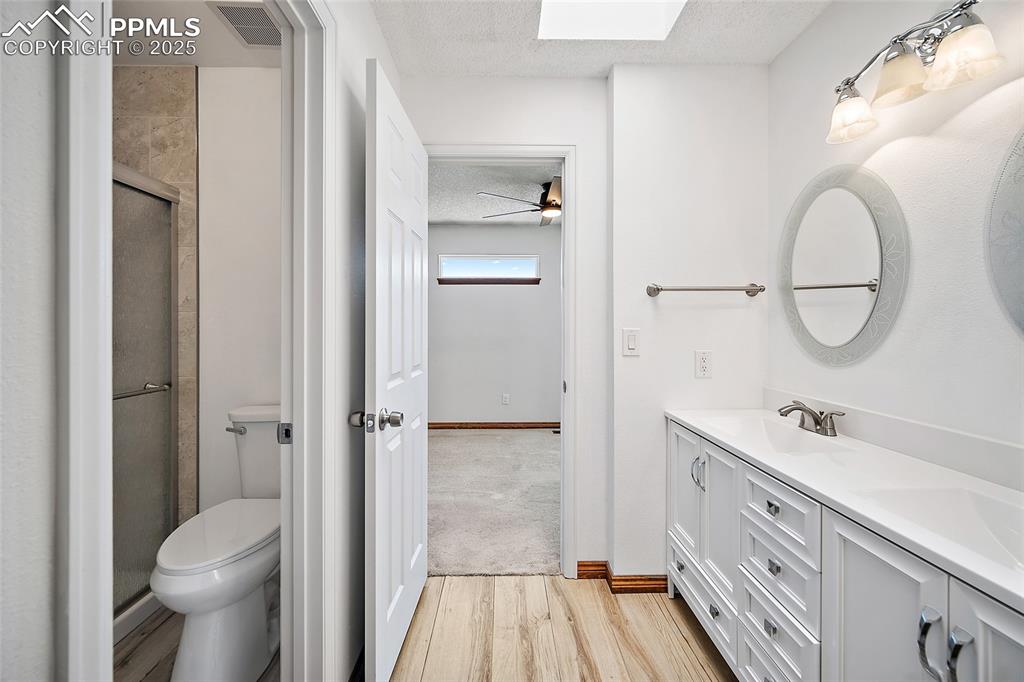 Image 21 of 41: Full bathroom featuring a textured ceiling, a skylight, wood finished floor