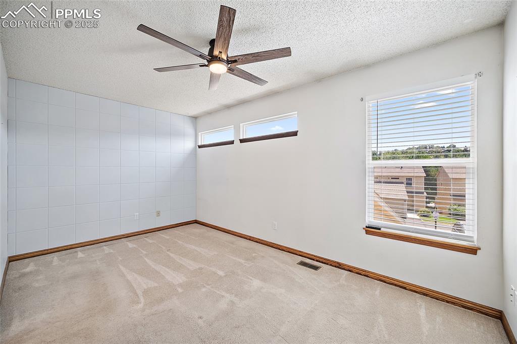 Image 23 of 41: Empty room with a textured ceiling, carpet, and a ceiling fan