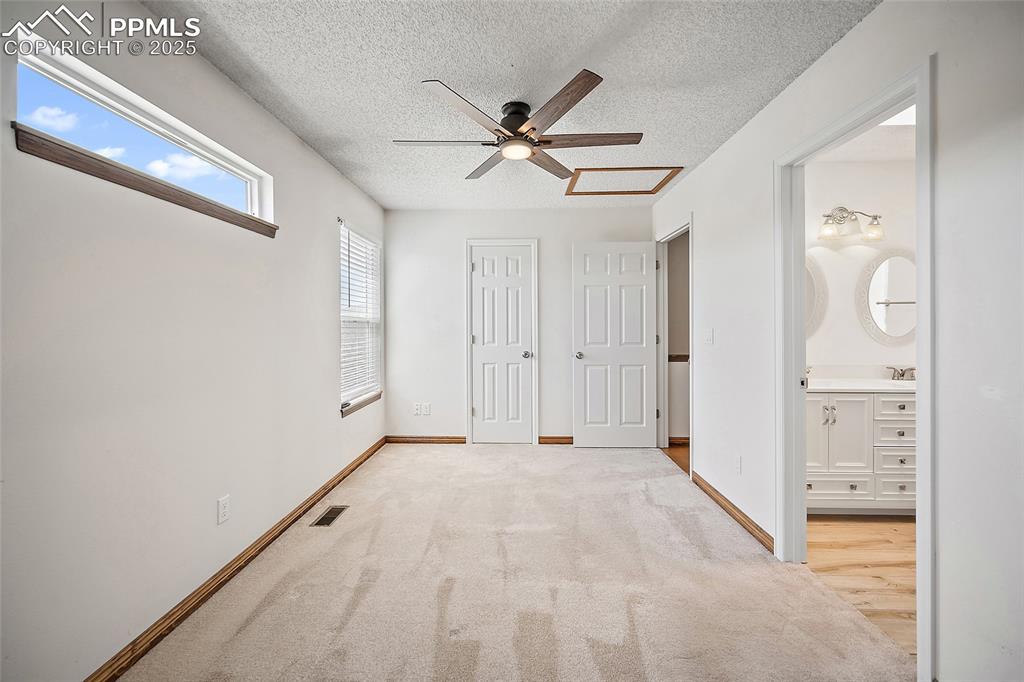 Image 25 of 41: Unfurnished bedroom featuring a textured ceiling, carpet, a closet, ensuite