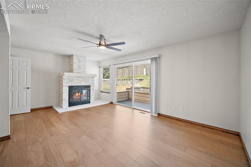 Image 7 of 41: Unfurnished living room featuring a textured ceiling, light wood-style floo