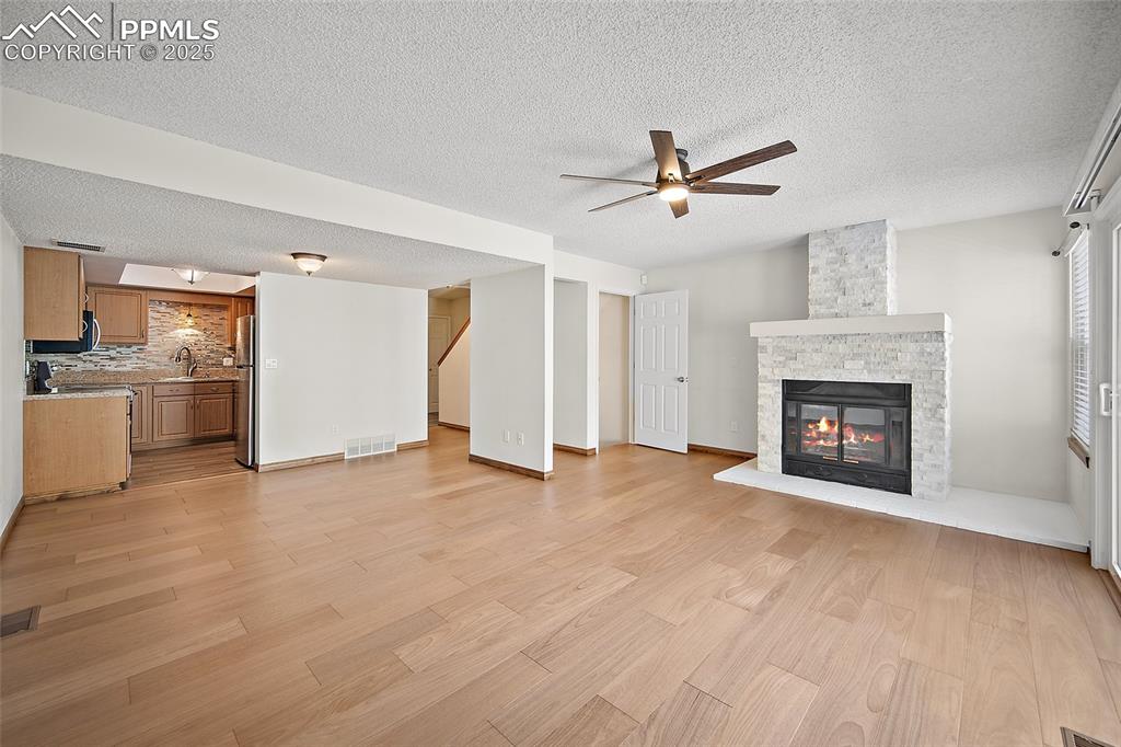 Image 9 of 41: Unfurnished living room with light wood-style flooring, a stone fireplace, 