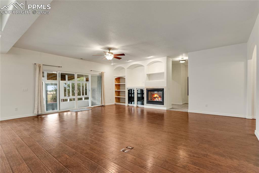 Image 19 of 48: Unfurnished living room with built in features, a multi sided fireplace, ha