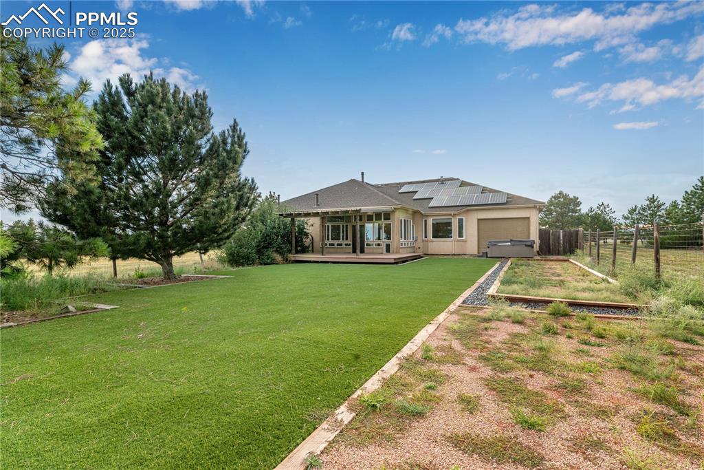 Image 2 of 48: Back of house featuring a wooden deck, solar panels, an attached garage, dr