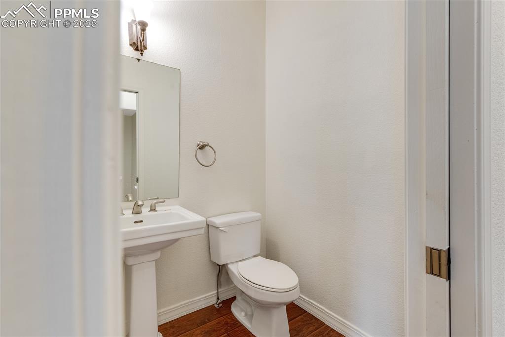 Image 20 of 48: Half bath featuring dark wood-style floors and a textured wall