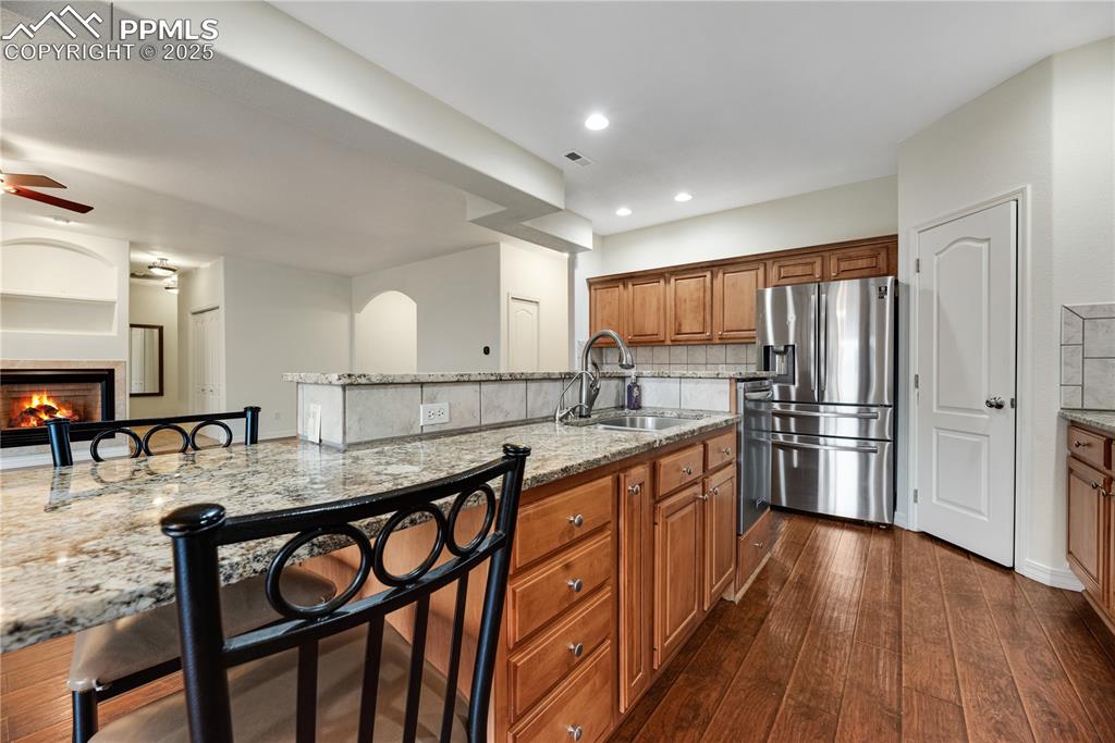 Image 22 of 48: Kitchen featuring brown cabinetry, light stone countertops, tasteful backsp