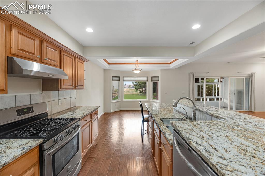 Image 23 of 48: Kitchen featuring a tray ceiling, appliances with stainless steel finishes,