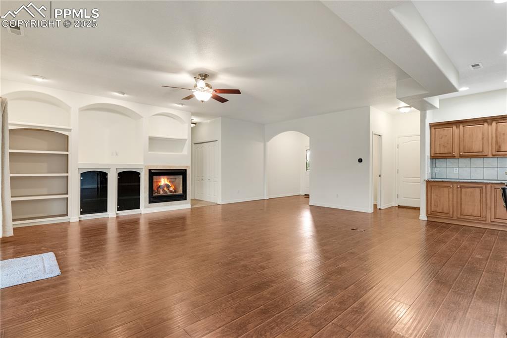 Image 36 of 48: Unfurnished living room featuring built in shelves, recessed lighting, a gl