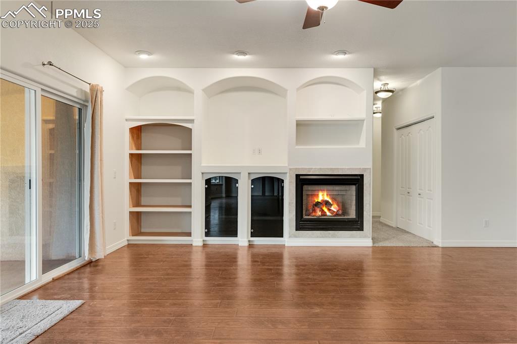Image 37 of 48: Unfurnished living room featuring built in features, a multi sided fireplac