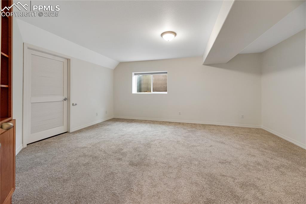 Image 46 of 48: Spare room with light carpet and vaulted ceiling
