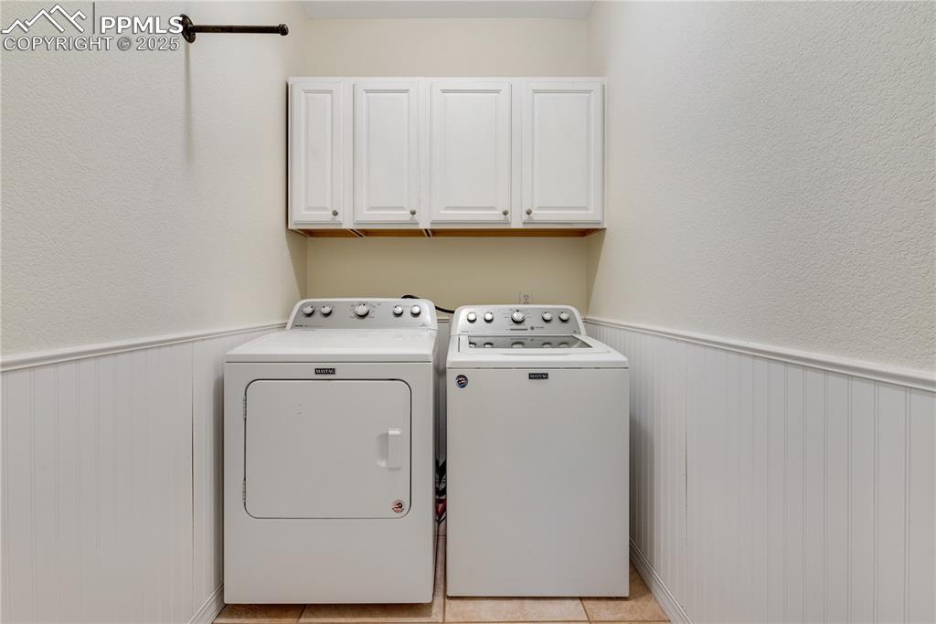 Image 48 of 48: Laundry room with a textured wall, cabinet space, separate washer and dryer