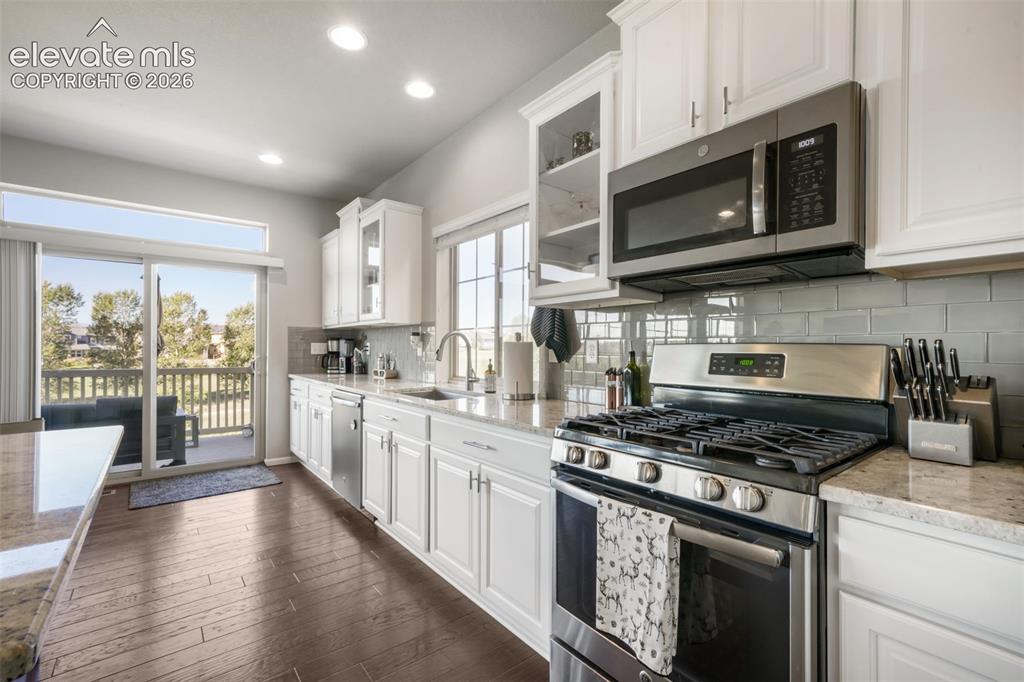 Image 10 of 48: White cabinetry, stainless steel appliances, wood-finish flooring, light-co