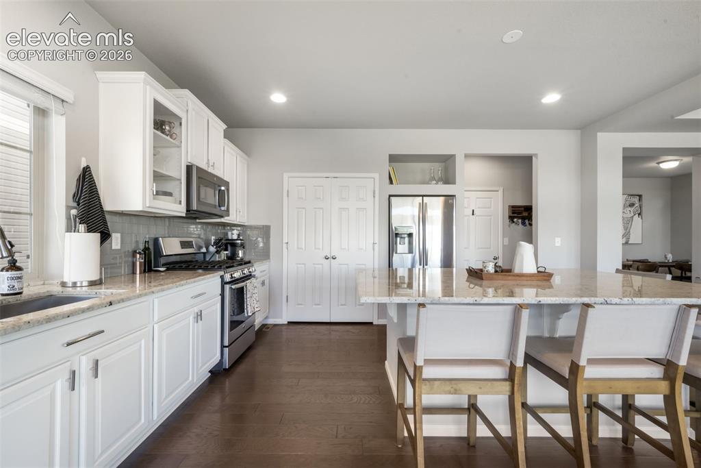 Image 13 of 48: Kitchen featuring wood-finish flooring, white cabinetry, a large kitchen is