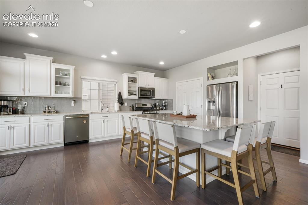 Image 14 of 48: Spacious kitchen featuring white cabinetry, stainless steel appliances, woo