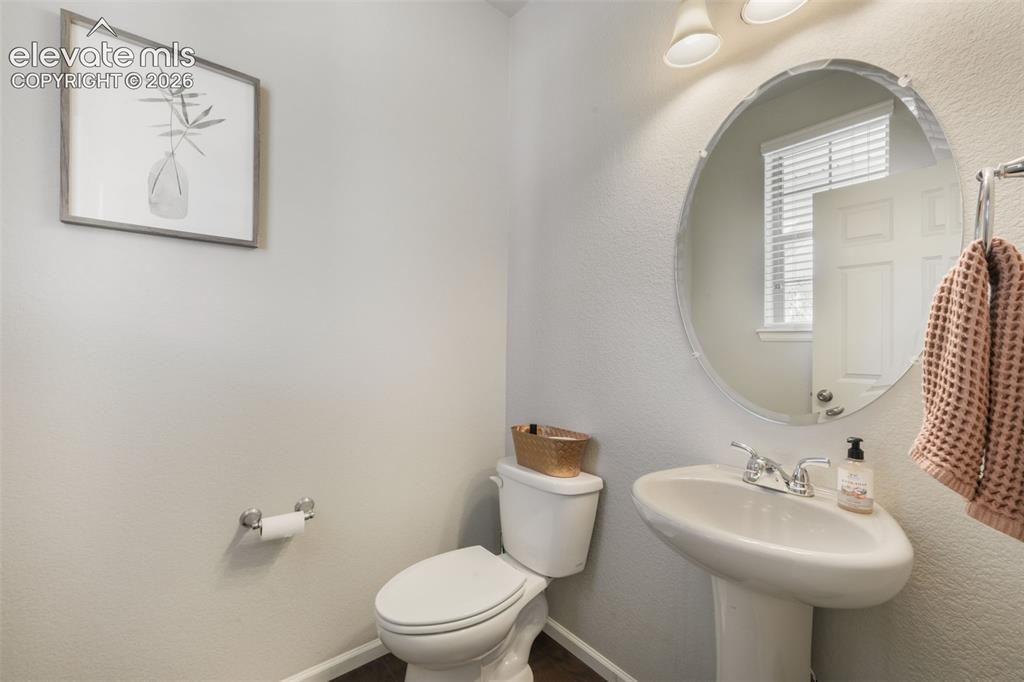 Image 18 of 48: Pedestal sink with chrome fixtures, oval mirror, wall-mounted light fixture