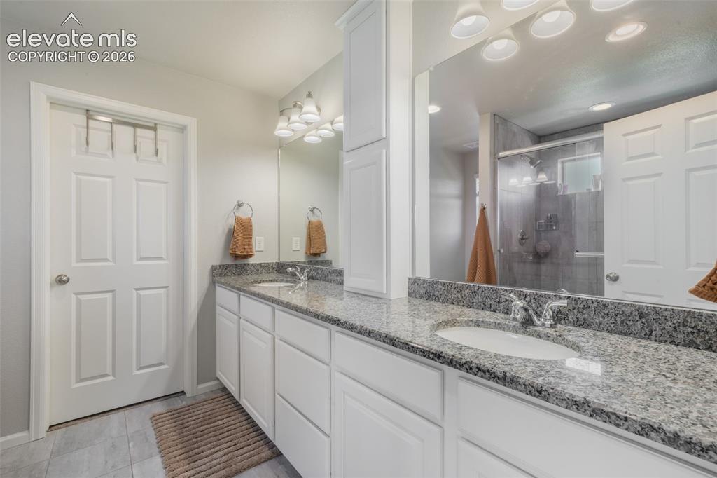 Image 27 of 48: Dual vanity with granite countertops, undermount sinks, and white cabinetry