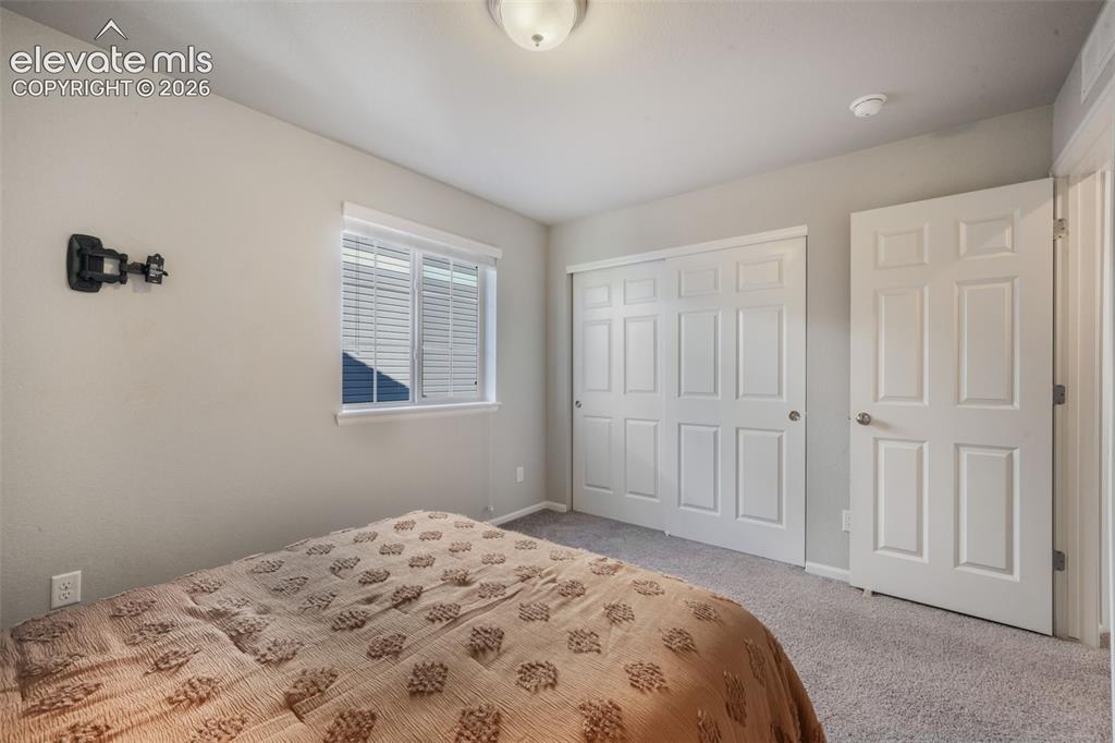 Image 29 of 48: Light-colored walls, carpet flooring, a window with blinds, and white panel