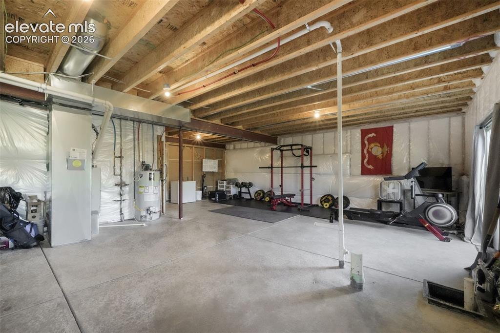 Image 37 of 48: Unfinished lower level with exposed ceiling joists, concrete flooring, and