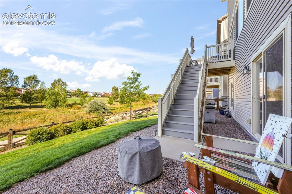 Image 41 of 48: Ground-level patio with gravel landscaping, a grass slope, and an elevated 
