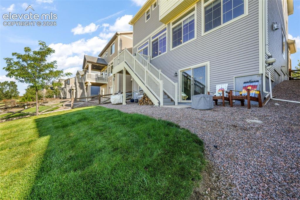 Image 44 of 48: Expansive grassy lawn with a gravel patio featuring a sliding glass door an
