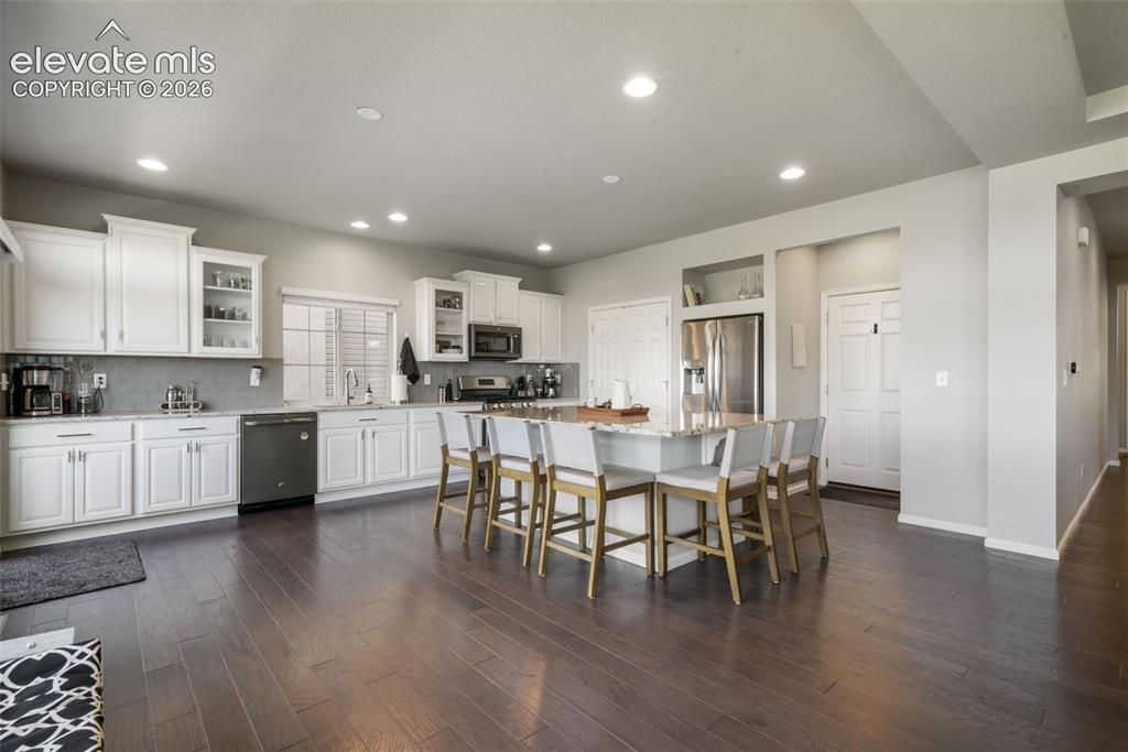 Image 8 of 48: Kitchen featuring wood-finish flooring, white cabinetry, a large center isl