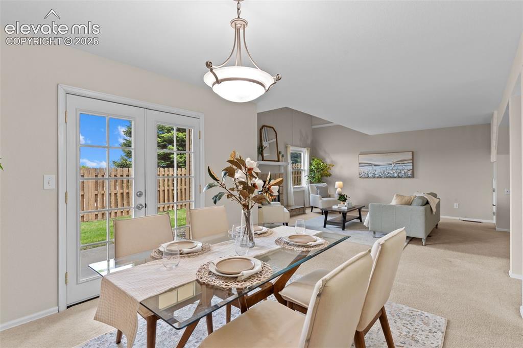 Image 10 of 32: Dining area with glass-paneled patio doors opening to a fenced yard