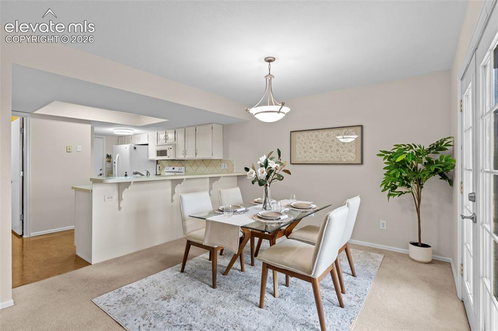 Image 11 of 32: Dining area with a kitchen pass-through, featuring a brushed nickel chandel