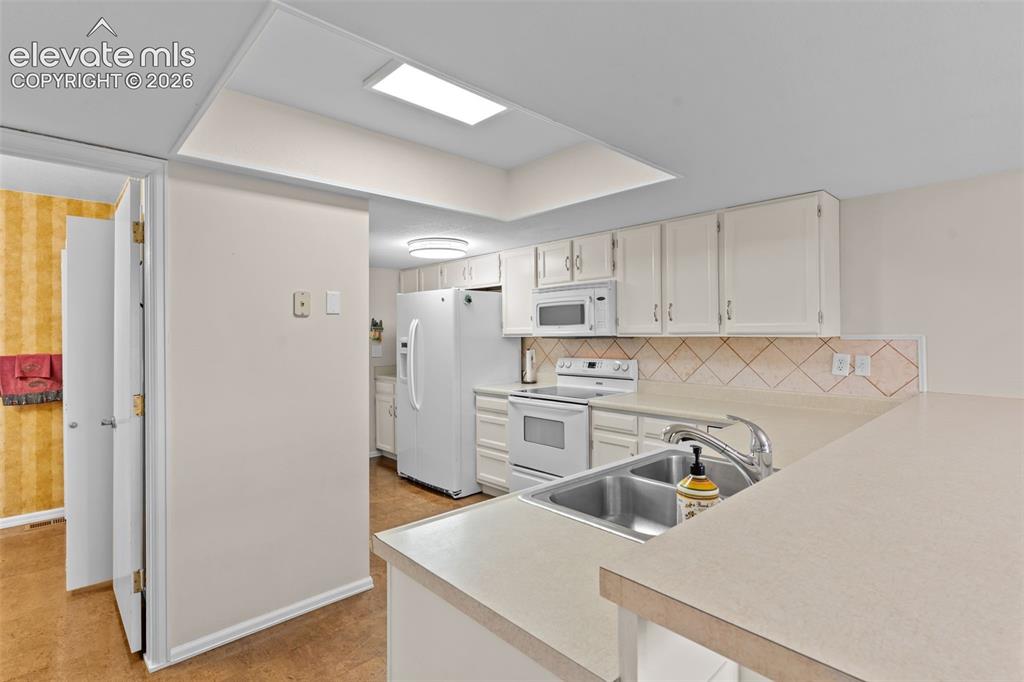 Image 12 of 32: Kitchen featuring white cabinetry, a double basin stainless steel sink, lig