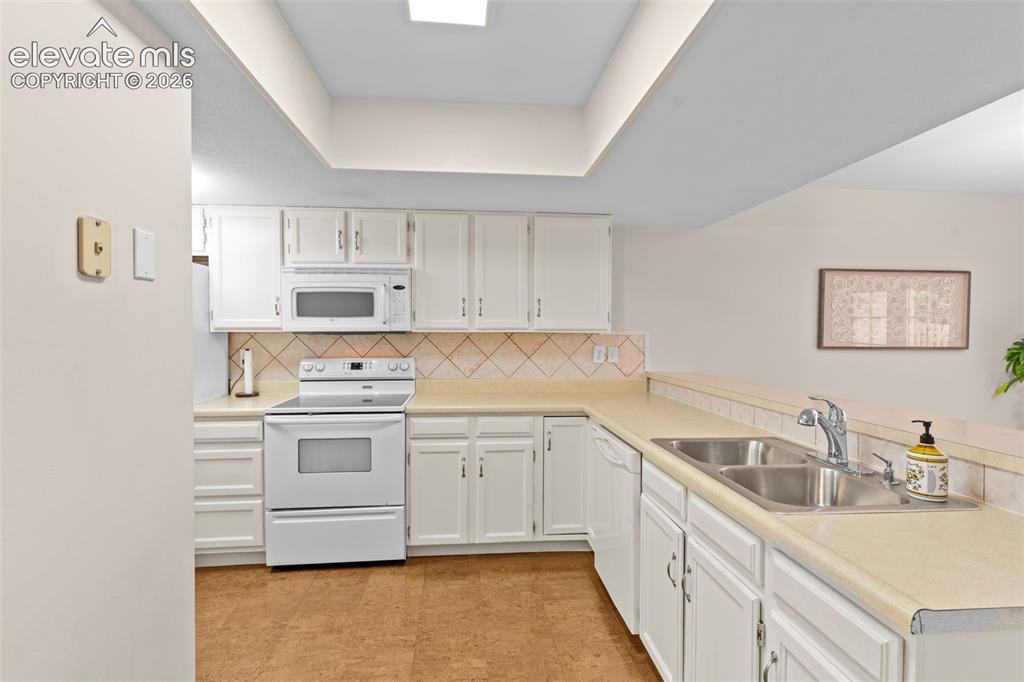 Image 13 of 32: Kitchen featuring white cabinetry, light countertops, and a full suite of w
