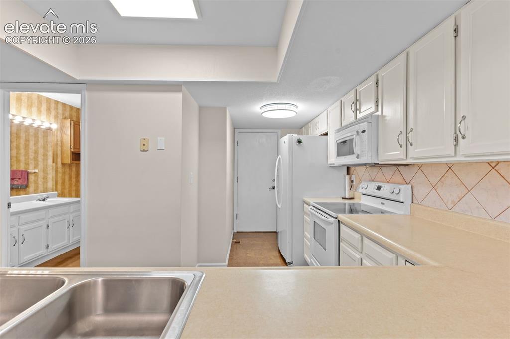 Image 14 of 32: Kitchen featuring white cabinetry, light-toned countertops, a stainless ste