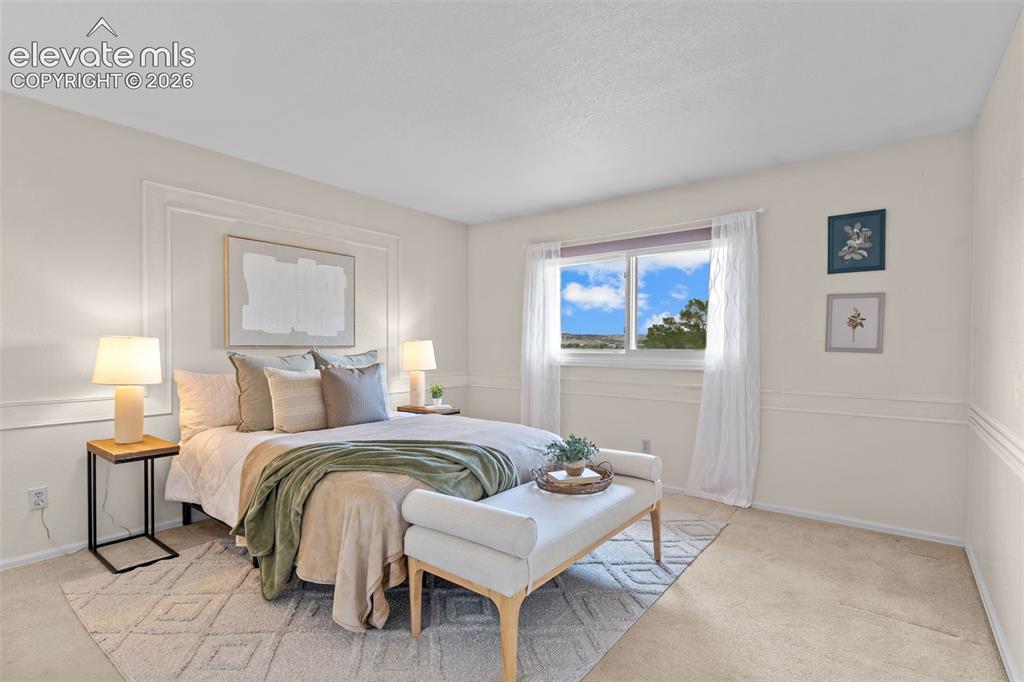 Image 15 of 32: Neutral-toned bedroom featuring wainscoting details and a large window with