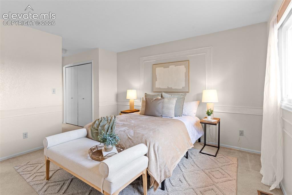 Image 16 of 32: Light-filled bedroom featuring white wall paneling, a large window, bi-fold