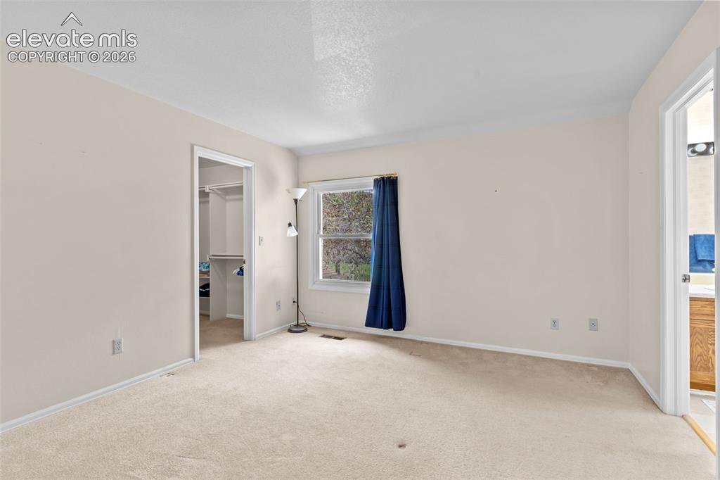 Image 18 of 32: Carpeted room featuring neutral wall tones, a large window, and an open doo