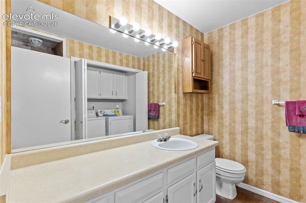Image 21 of 32: Bathroom featuring a vanity with a laminate countertop, integrated sink, an