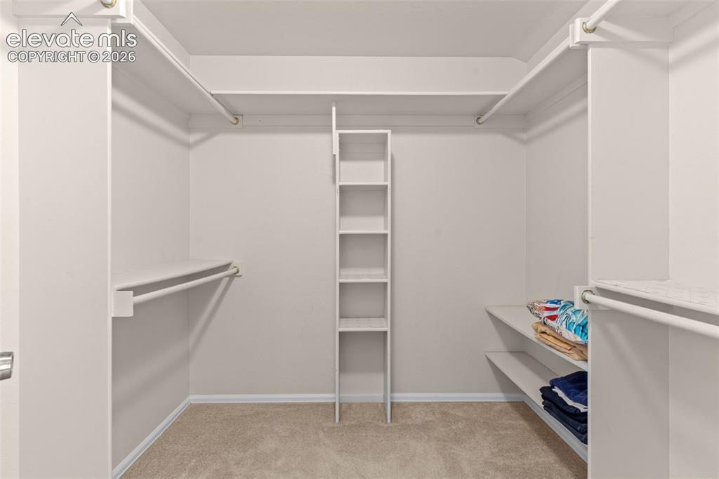Image 23 of 32: Walk-in closet featuring built-in shelving, multiple hanging rods, and neut