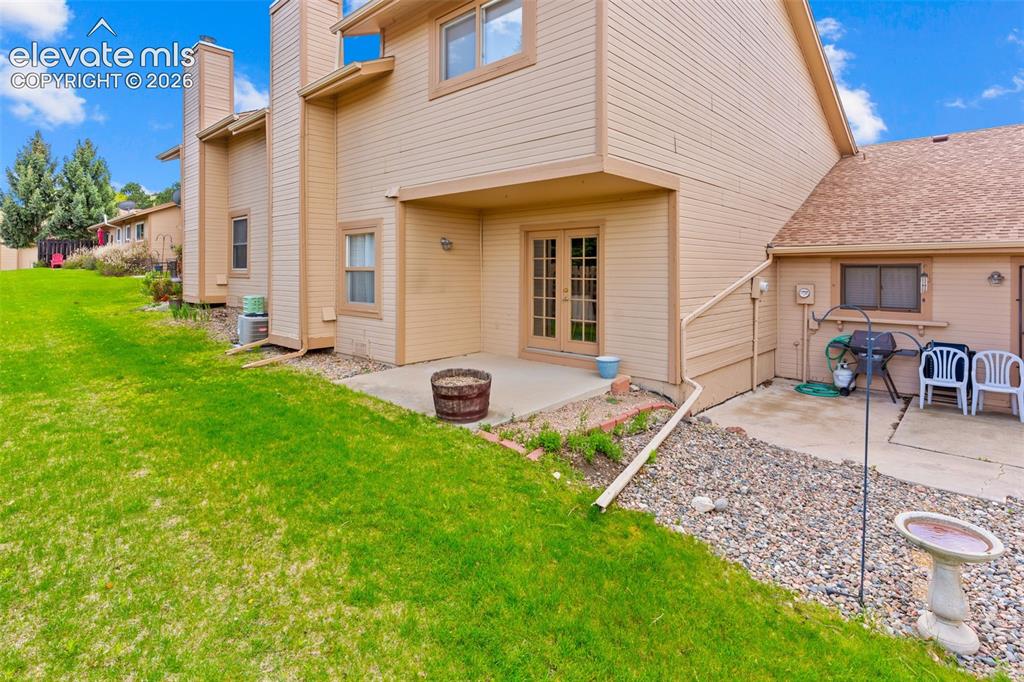 Image 24 of 32: Rear exterior with a concrete patio, French doors, and a covered porch