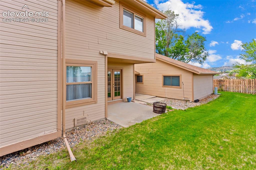 Image 26 of 32: Expansive green lawn with a wood fence bordering the property