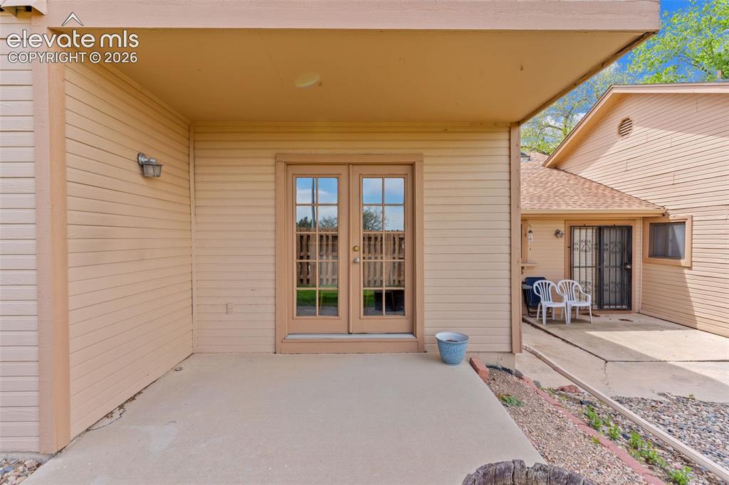 Image 27 of 32: Covered concrete patio featuring double glass-paned doors with grid inserts