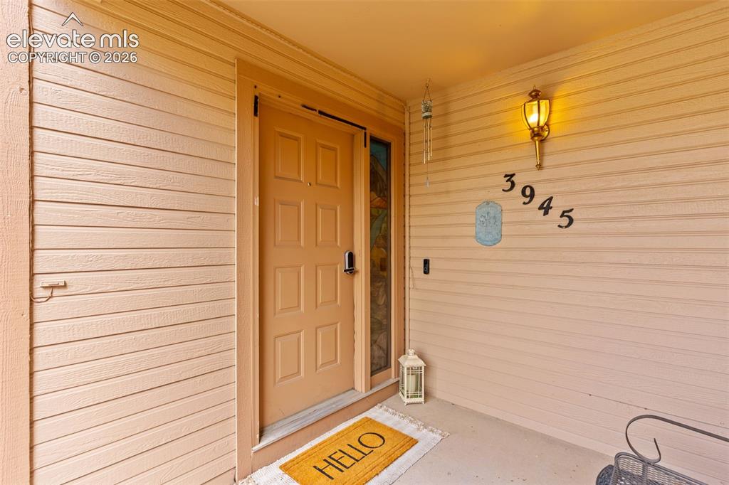Image 4 of 32: Covered entry featuring horizontal siding and a panel-style door with decor
