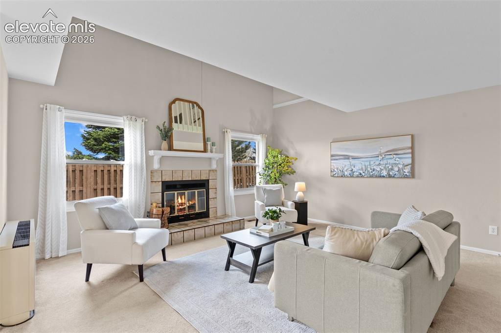 Image 5 of 32: Living area featuring a brick-surround fireplace with a white mantel, vault