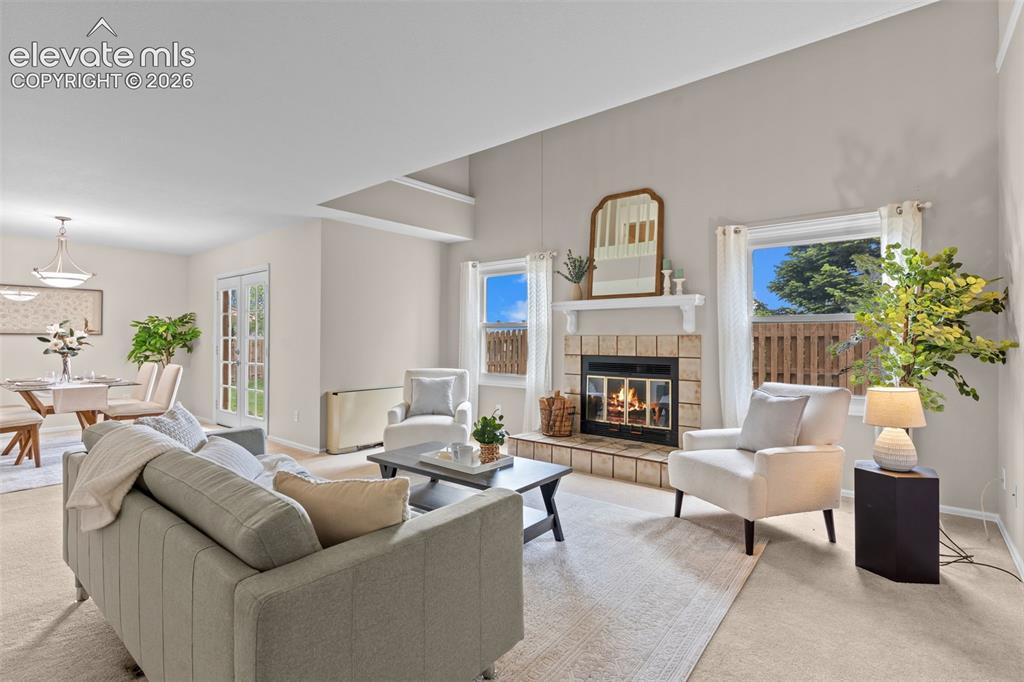 Image 6 of 32: Living area featuring a tiled fireplace with mantel, vaulted ceilings, and 