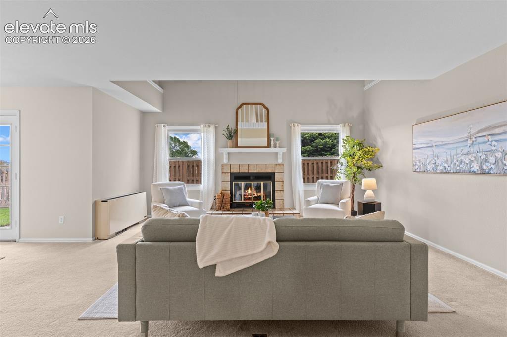 Image 7 of 32: Living area featuring a brick fireplace with a white mantel, two windows wi